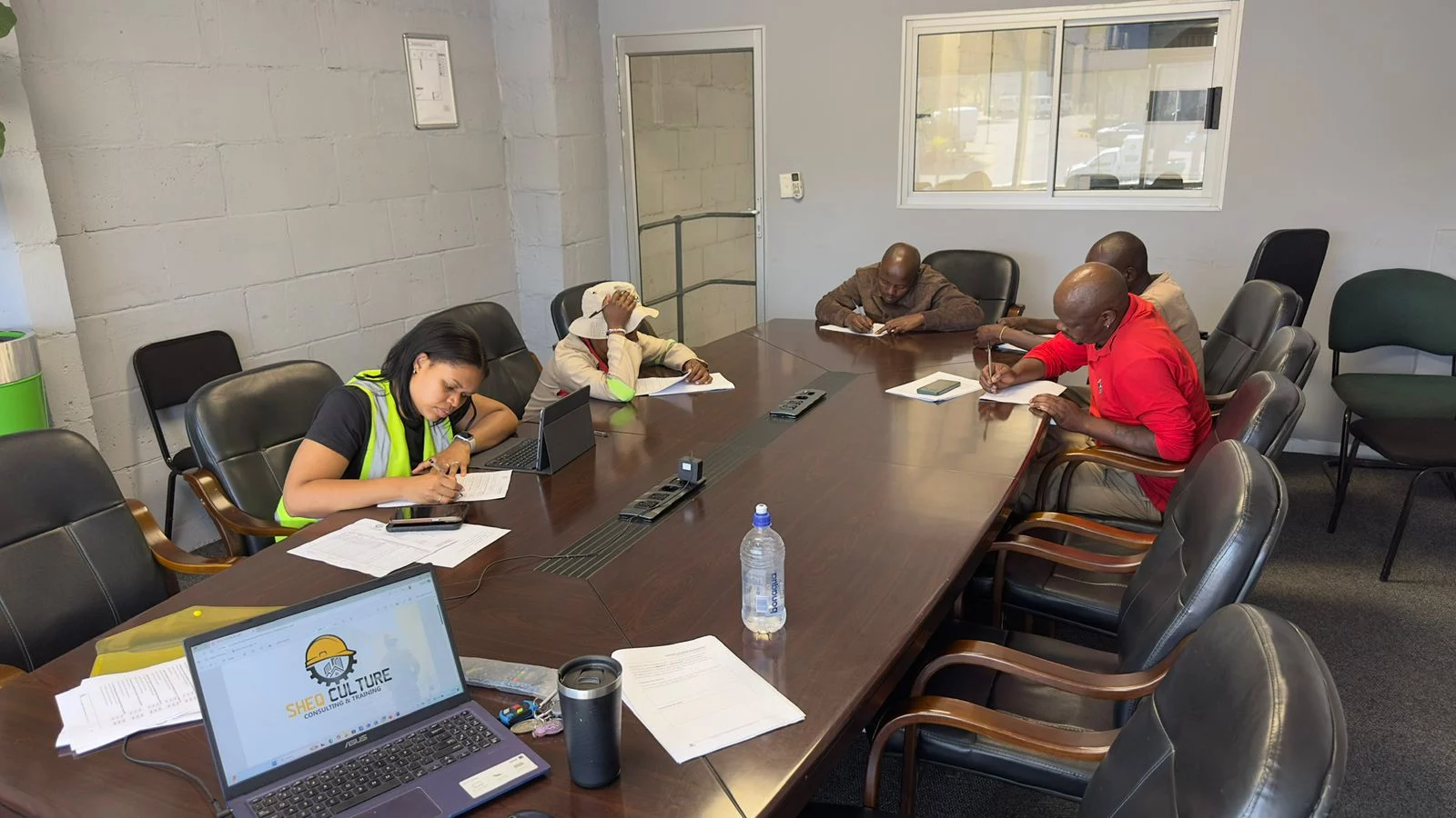 A group of people sitting and working around a boardroom table.