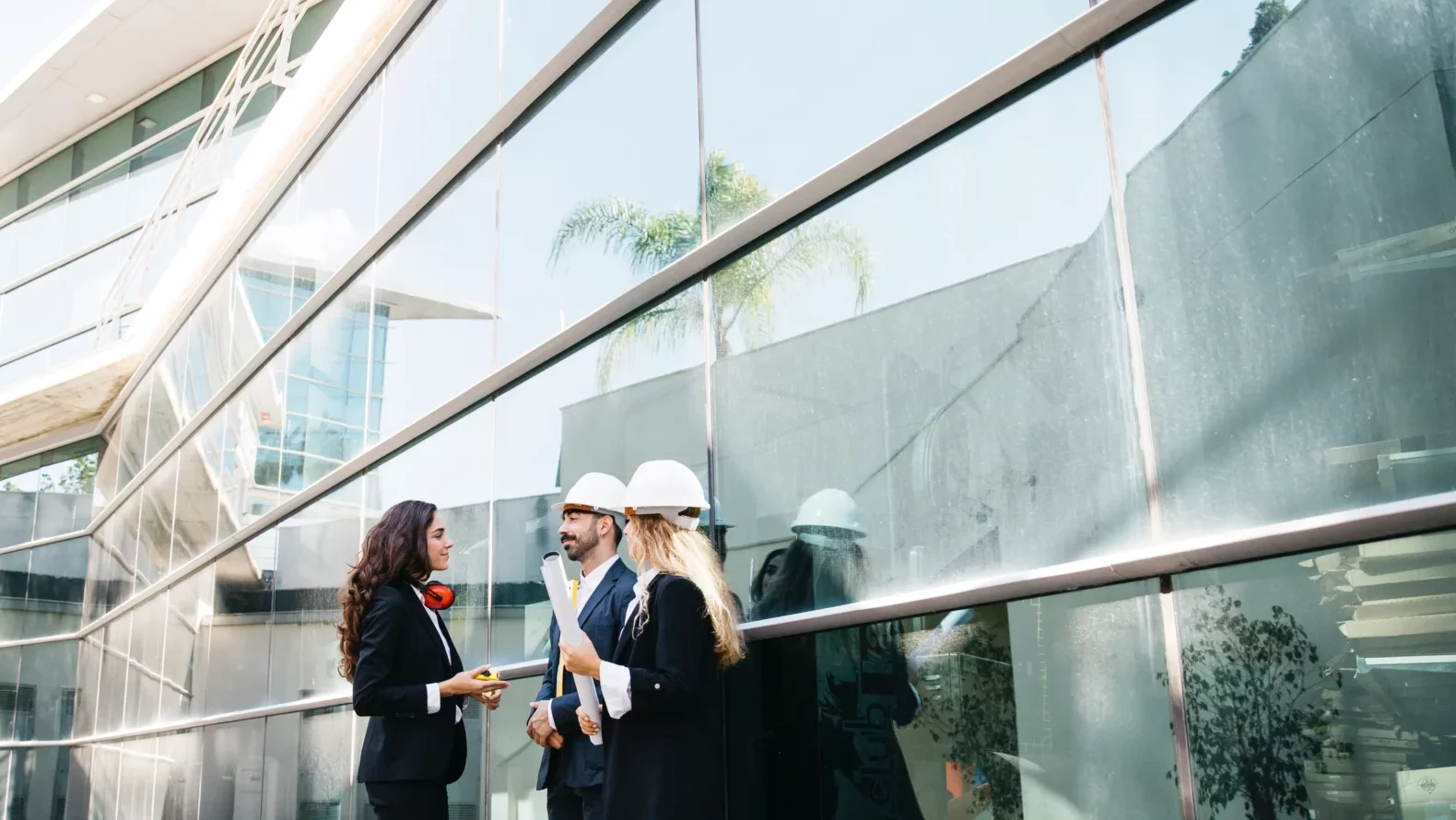 Architects wearing helmets in front of a building.
